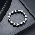 Gros plan de perles d'hématite cubiques sur un plateau en bois avec une plume noire - Style de Perles Cubiques (S733-D)