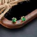 Macro shot of green zircon stud earrings with gold four-prong setting on a dark surface - Four Prong Green Stone Earrings (X864-B) / Gold Pair