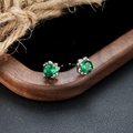 Detailed close-up of emerald green zircon studs with six-prong silver-tone setting - Four Prong Green Stone Earrings (X864-A) / Silver Pair