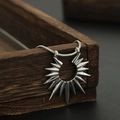 Détail du pendentif soleil argenté sur chaîne serpent sur une boîte en bois - Style Collier d'Aile (L884-A)