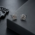 Close-up of vintage silver stud earrings with deep red gemstones and octagonal borders - Red