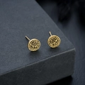 Macro shot of gold lion head stud earrings with embossed details on a textured box - Antique Gold