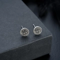 Macro shot of vintage silver wolf head stud earrings with embossed Viking rune textures - Antique Silver