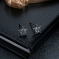 Macro shot of gun-black star earrings with micro-inlaid white zircons on leather - Gunmetal