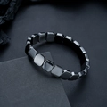 Close-up of polished black hematite square bead bracelet on a textured background - Rounded Square Style (S528-A)