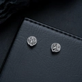 Detail of vintage silver scorpion studs with embossed patterns on black leather texture - Clip-On Earrings / Silver