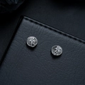 Detailed view of silver scorpion relief stud earrings on a textured leather background - Clip-On Earrings / Gunmetal
