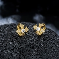 Makroaufnahme von goldenen Kreuz-Ohrringen mit Zirkonia auf schwarzem Lavastein - Gold