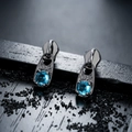 Macro detail of gunmetal zipper pull earrings with blue zircon stones and engraved text - Gunmetal