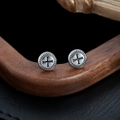 Dettaglio macro di orecchini a croce argento vintage con motivi neri su sfondo in legno scuro - Pezzo Singolo / Argento