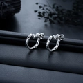 Macro shot of silver Mobius screw-back ear clips on a premium black leather texture base - Silver