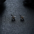 Macro detail of gunmetal star earrings with yellow gemstone inlay on dark surface - X1060-D (Star Stud) / Gun Black Gold