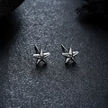Detailed view of silver five-star stud earrings on a textured dark grey background - X1060-A (Pentagram Stud) / Silver