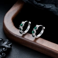 Macro shot of silver hoop earrings with emerald green gemstones and cubic zirconia accents - Silver Green Zirconia Pair