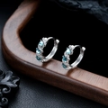 Detail view of silver hoop earrings with blue oval stones on a dark wooden stand - Silver Blue Zirconia Pair