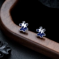 Macro shot of blue enamel puzzle earrings with silver-tone edges on wooden stand - Blue Silver
