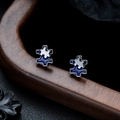 Macro shot of silver puzzle-shaped stud earrings with blue and white enamel dripping oil - Blue Gun Black