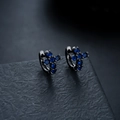 Detailansicht der schwarzen Creolen mit blauem Zirkonia-Kreuz auf dunklem Hintergrund - Gunmetal Schwarz-Blauer Strass