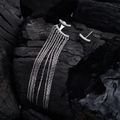 Asymmetrische lange Quasten-Silberohrringe mit Zirkonia auf dunklem Holzhintergrund - 925er Silber / Silber
