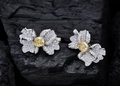 Makroaufnahme von silbernen Blumenohrringen mit gelbem Edelstein auf Holzkohle - 925er Silber / Gelb