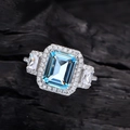 S925 Silberring mit blauem Edelstein im Smaragdschliff und Diamant-Halo-Fassung - US 7 / Himmelblau
