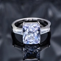 Bague trois pierres avec diamant taille radiant et anneau en argent sur fond noir poli - Lavande