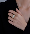 Close-up of wide gold-plated ring with micro-pave crystals on a black suit sleeve - US 6 / Gold