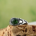 Macro view of men's retro titanium steel ring with an oval green flame gemstone inlay - Dark Green