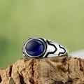 Macro detail of men's vintage titanium steel ring with oval blue gemstone on cork base - Blue Stone