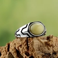 Macro shot of vintage titanium steel ring with green gemstone on rustic bark - Cream Stone
