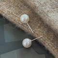 Primer plano detallado del sello S925 y pendientes de perlas blancas sobre tejido de punto - Estilo Redondo 8mm (EHL125) / Plata 925