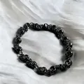 Dettaglio macro del bracciale a teschio punk nero con chiusura a moschettone su seta - Nero