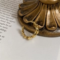 Detailansicht goldener gedrehter Croissant-Ring an Vintage-Metallstütze auf Magazinseiten - Einstellbar Offen / Kleines Gold