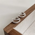 Macro shot of silver triple-layered twisted rope hoop earrings on a wooden display tray - 925 Silver / Silver