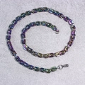 Rainbow plated stainless steel Cuban link chains in spiral layout on grey surface - Emperor Chain
