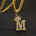 Gros plan du pendentif M hip-hop doré avec couronne et cristaux blancs brillants - Style M