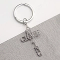 Vue macro porte-clés croix argentée avec découpe Amazing Grace sur fond en pierre - Argenté