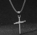 Détail du pendentif croix en acier titane avec design industriel sur fond noir texturé - Style de Design Croix de Clou / Argenté