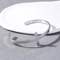 Brazalete minimalista de acero inoxidable con diseño de cruz central y textura mate - Color Acero