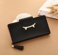 Detail of black pebbled leather wallet with gold cat-ear buckle and stylish tassel charm - Black