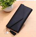Detailed view of black envelope wallet featuring a gold heart pendant and long tassel charm - Black