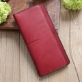 Minimalist deep red leather long wallet for women on a rustic wooden desk with decor - Burgundy