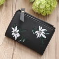 Close-up of black leather wallet featuring white daisy embroidery and gold zipper detail - Black