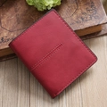 Macro shot of red pebble grain leather wallet with reinforced stitching on wooden desk - Burgundy