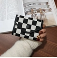 Foldable checkerboard wallet with black leather trim held by hand on wooden desk - Black and White Plaid