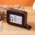Detalle de cartera en cuero granulado marrón con cremallera doble y ventana para identificador - café