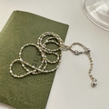 Macro detail of silver textured beads and golden smooth beads with heart charm on a chain - 7TL21 Scimitar Olive Bead 60CM