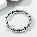 Detalle macro de pulsera abierta de alambre trenzado gris plata en estilo punk vintage - Distressed Vintage Thorn Style / Plata Antigua
