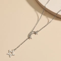Collar minimalista en Y con media luna de plata y colgante de estrella sobre fondo beige - Color Acero