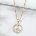 Detailweergave van de gouden peace-teken hanger met glinsterende kristallen aan een boxketting - Goud